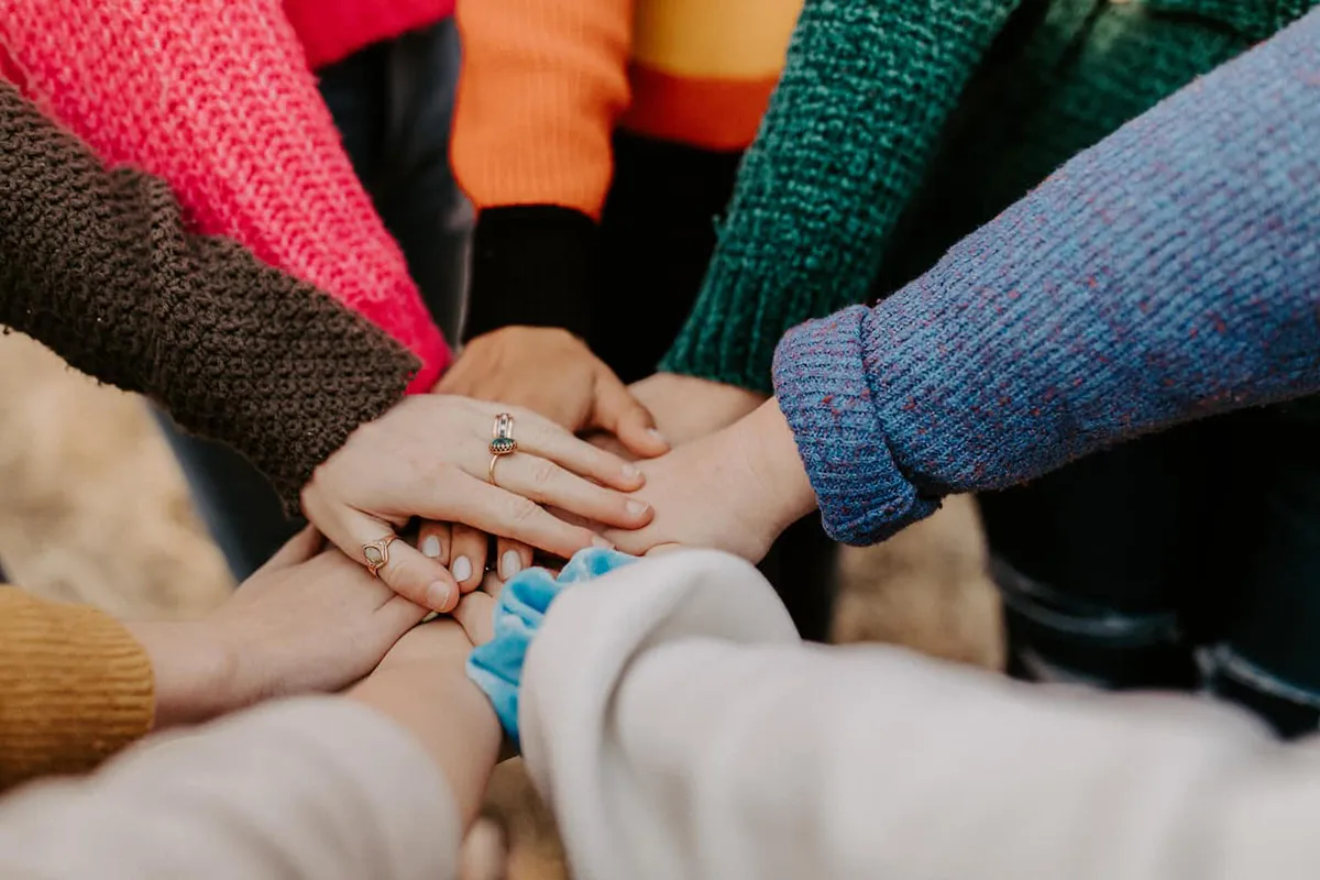 Group of people with arms/hands all together in the middle.