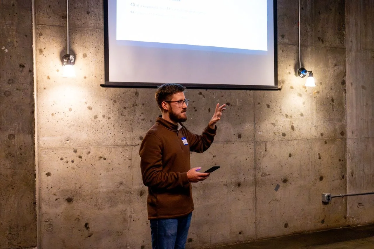 David gesturing while presenting under a projector screen